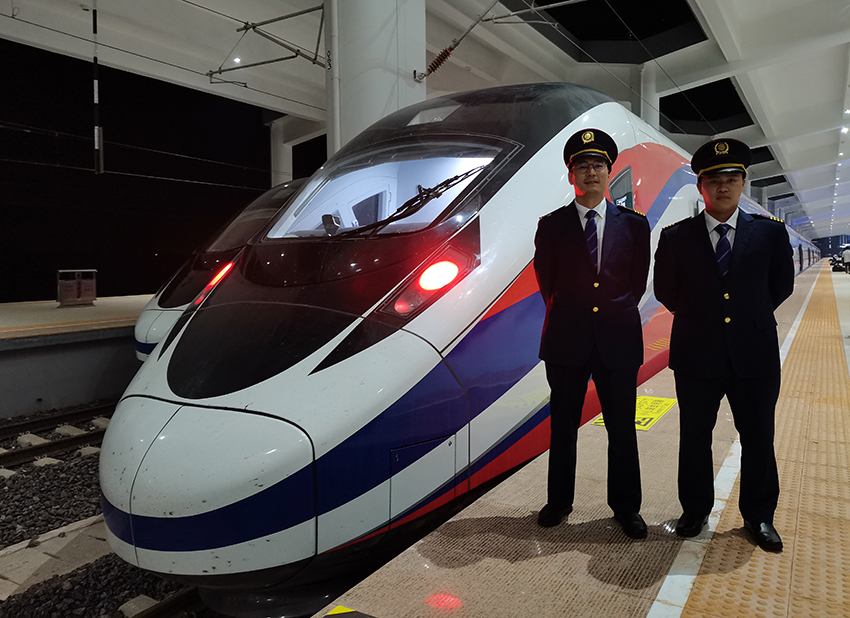 劉銀能（右一）與中國(guó)師父鄔俊鴻在動(dòng)車(chē)組前合影。受訪者供圖