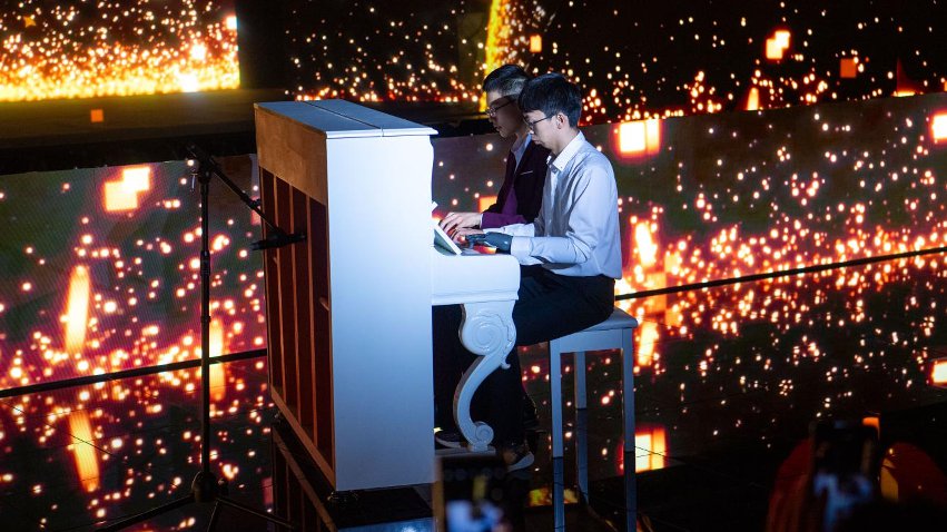 智能仿生手使用者古月與少年鋼琴家舒海峰合奏。主辦方供圖